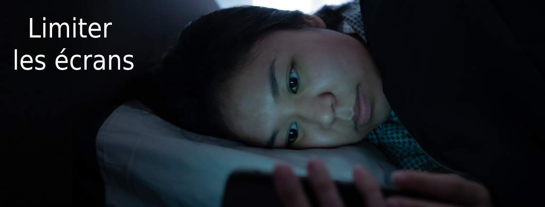 jeune femme regardant son écran de téléphone allongée dans son lit
